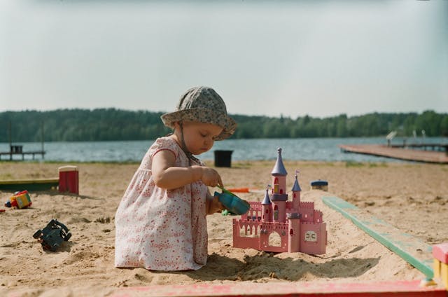 toddler playing beach sand building sandcastle